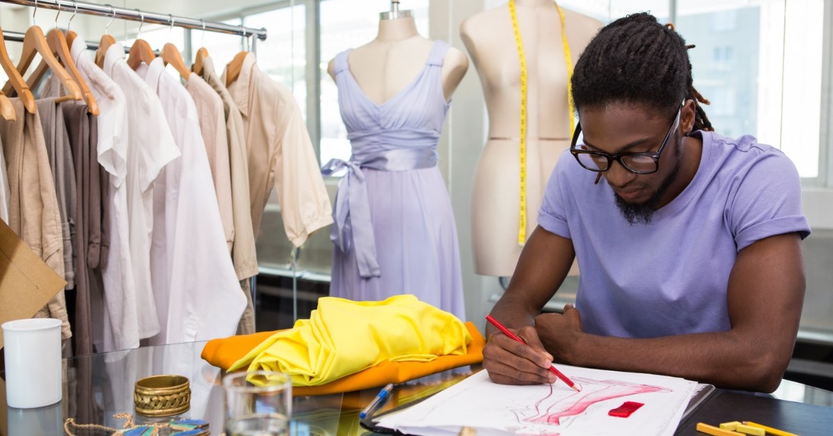 african american male designer in studio sketching new designs on book