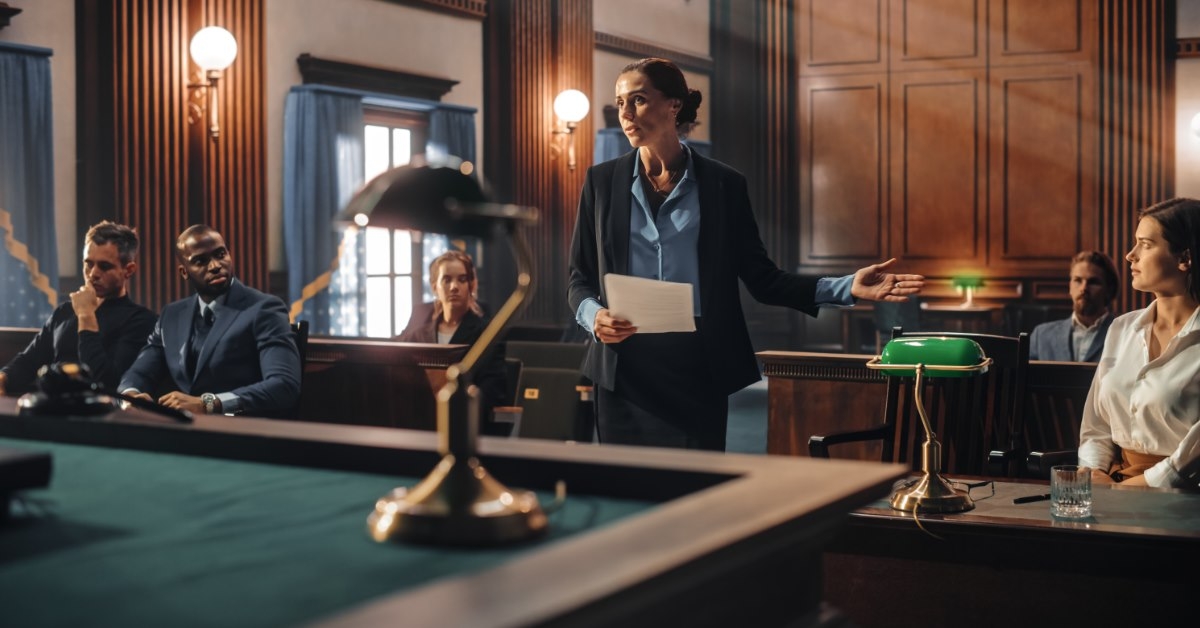 female lawyer standing in front of judge making speech in defense of client in court with people