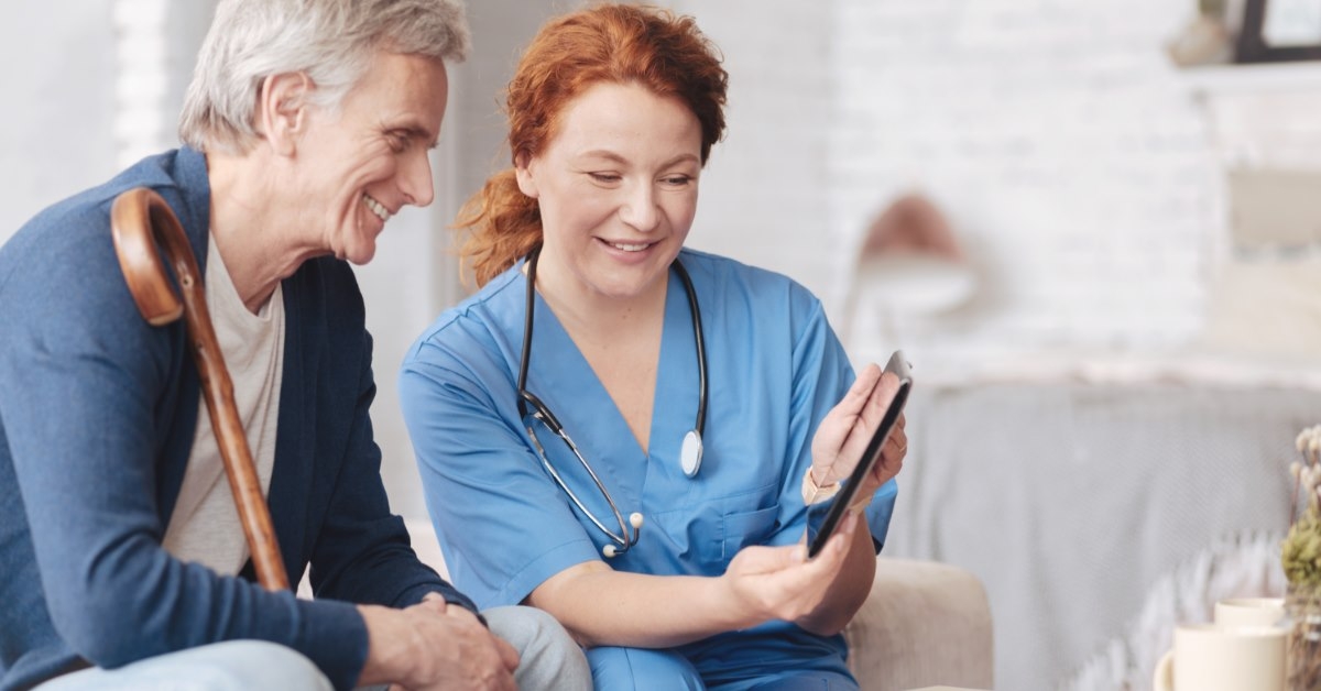nurse using tablet to show something to senior male patient