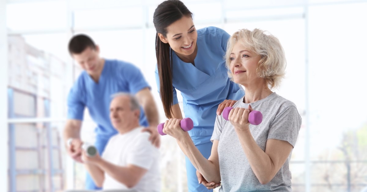 physiotherapists in rehab helping senior patients to lift