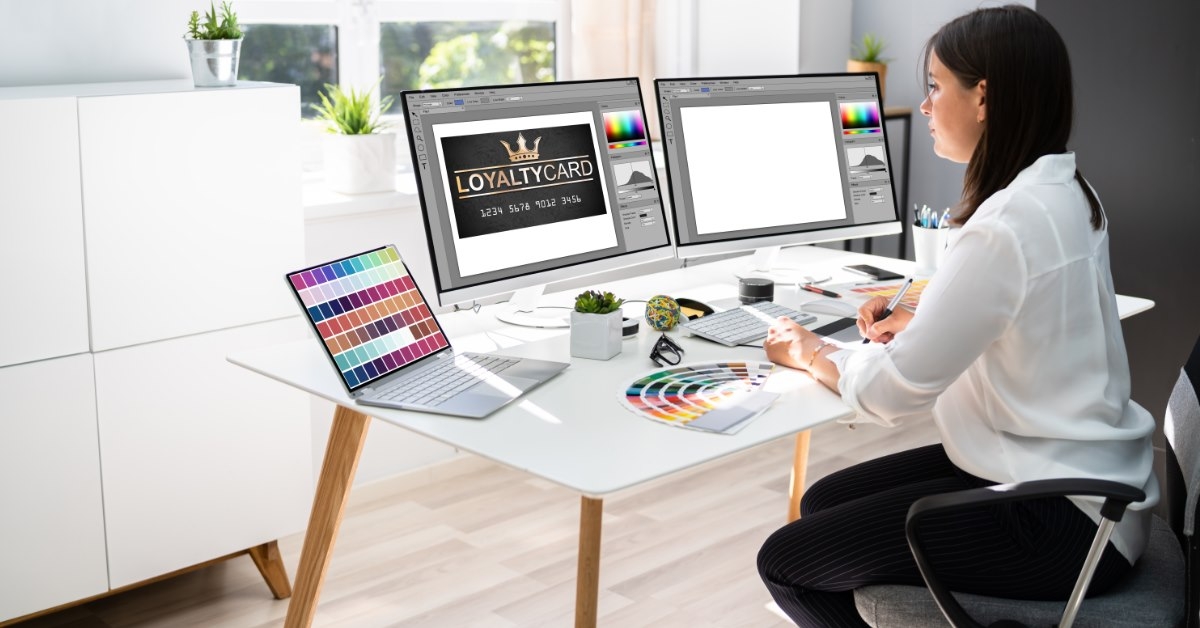 woman working on web designs using desktop on table with color codes on laptop