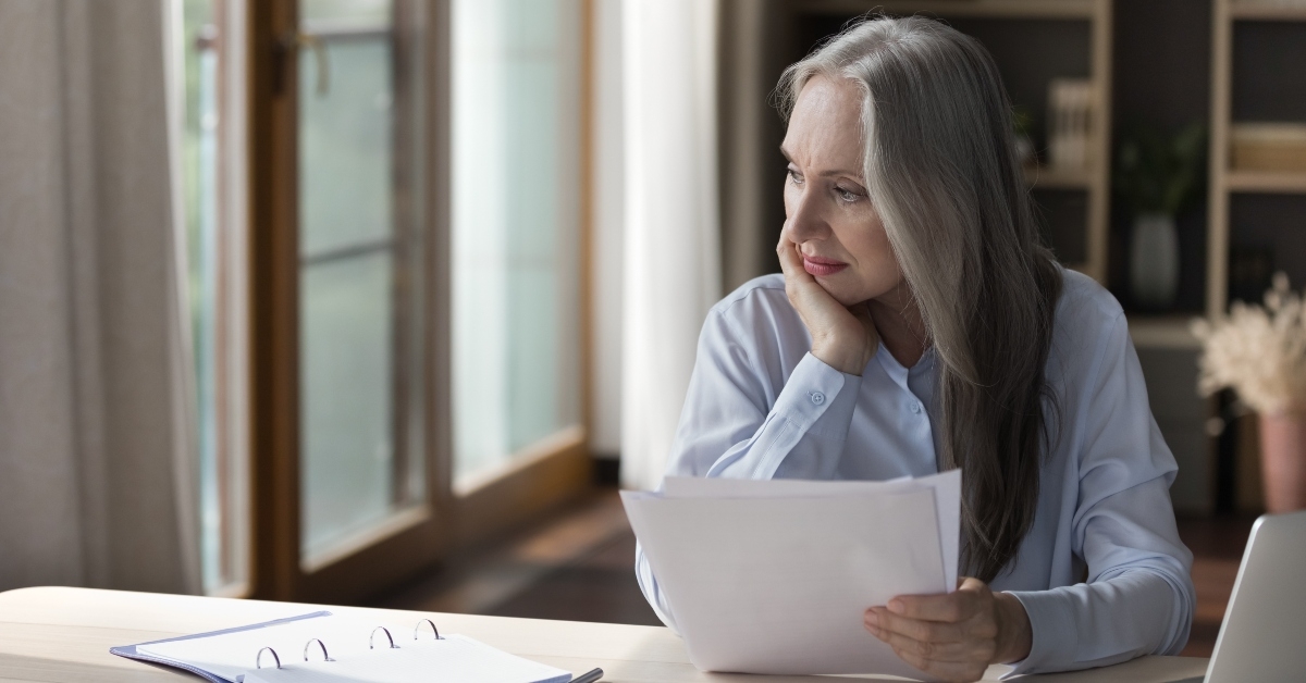 elderly retired woman thinking over paper documents
