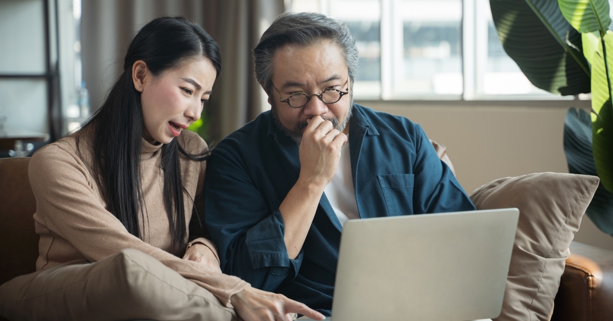 stressed middle-aged asian couple compute finances