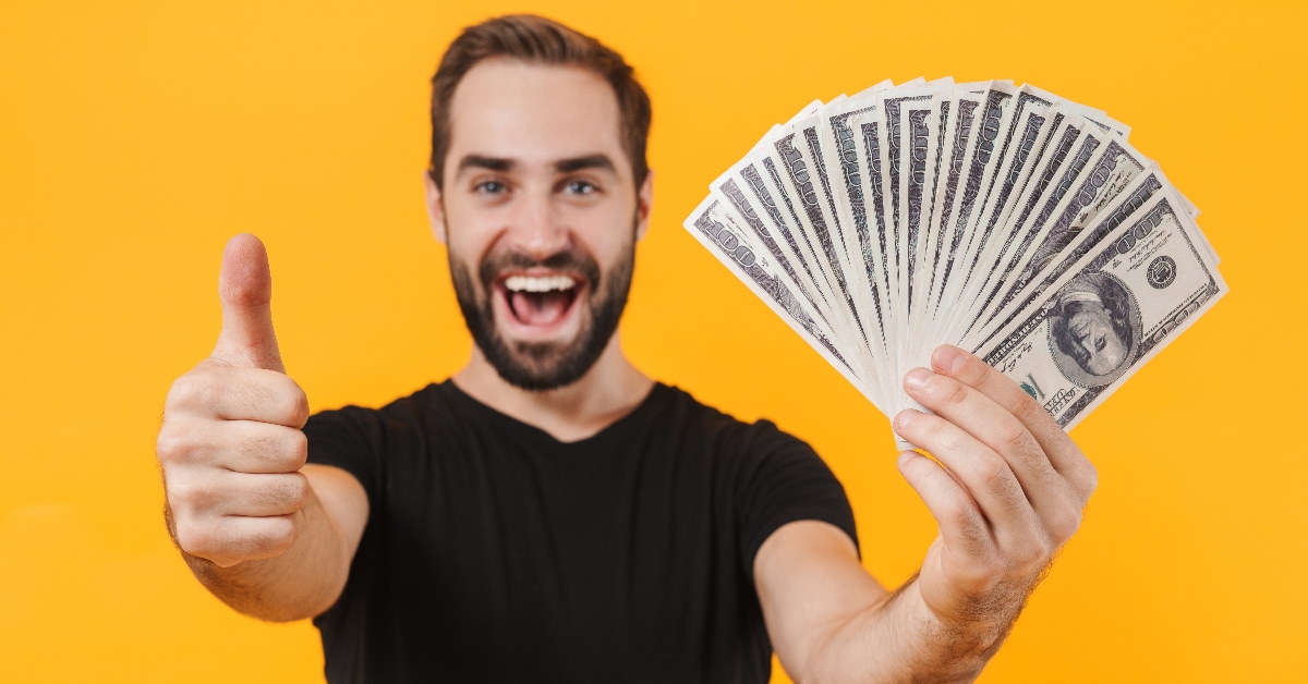 man holding money in hand while doing thumbs up 