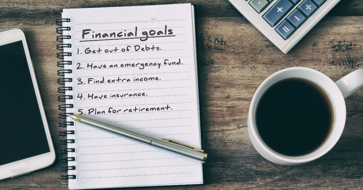 notebook on rustic wooden table with financial plans along with coffee calculator and smartphone