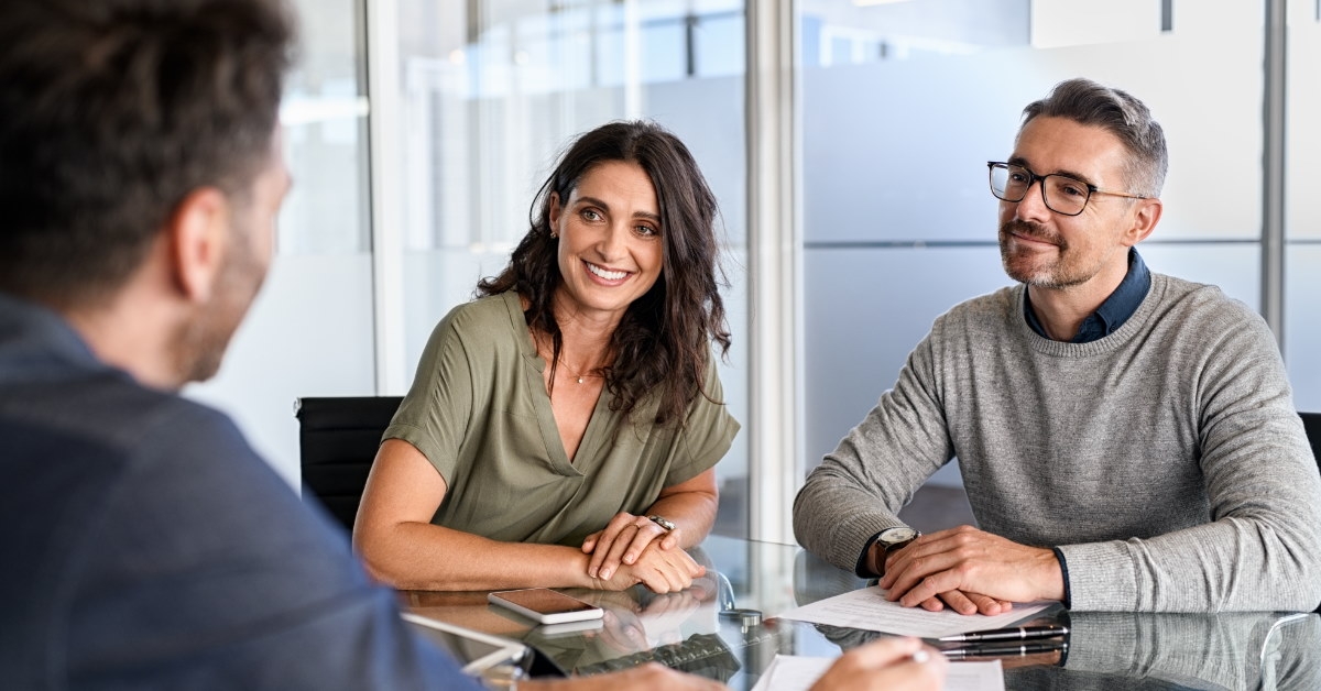 couple sitting at table in discussion with male financial advisor
