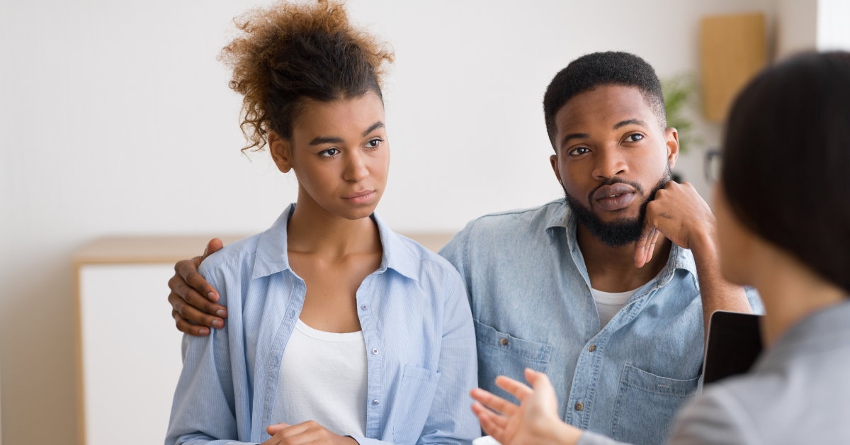 african american couple sitting in front of female financial advisor having discussion with papers and cup on table