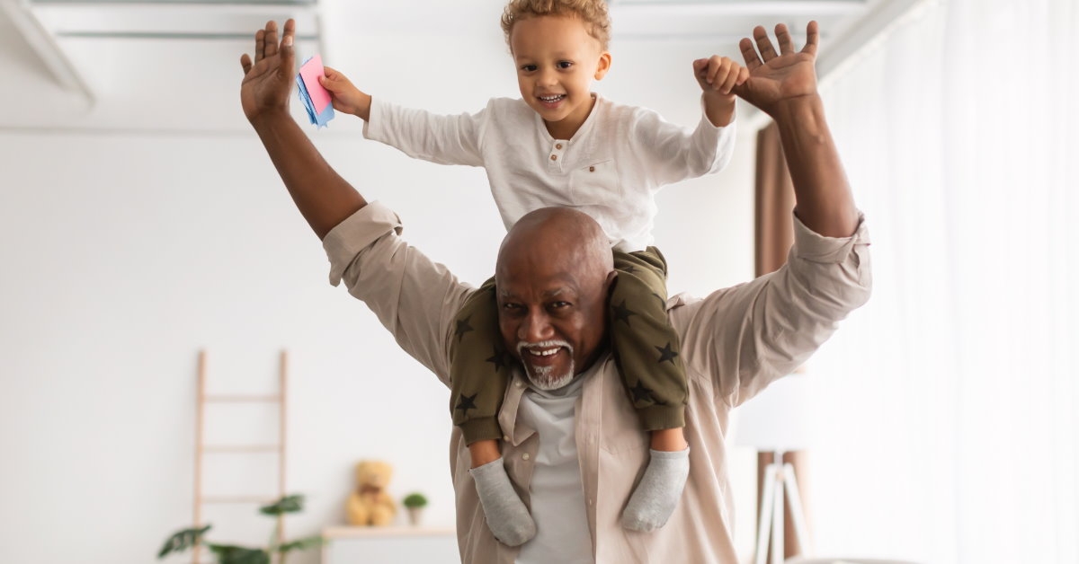 african american man playing with grandson while having him on shoulders