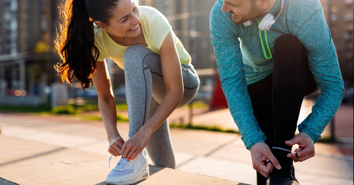 couple looking at each other tying laces for jogging outdoors