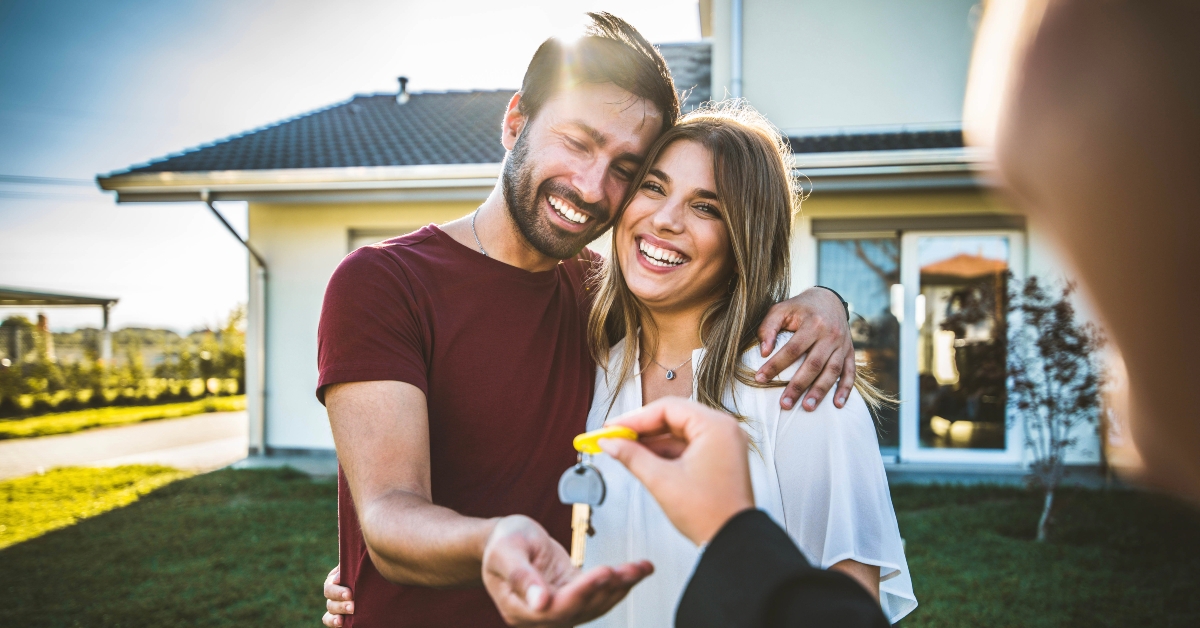 millennial couple receiving keys from realtor