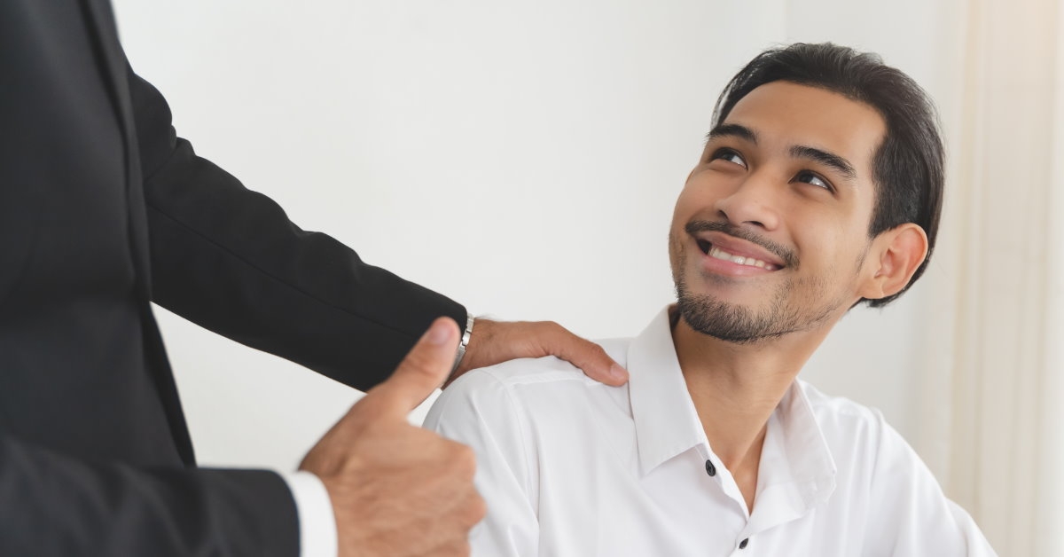 boss in black suit appreciating asian employee by doing thumbs up sign 