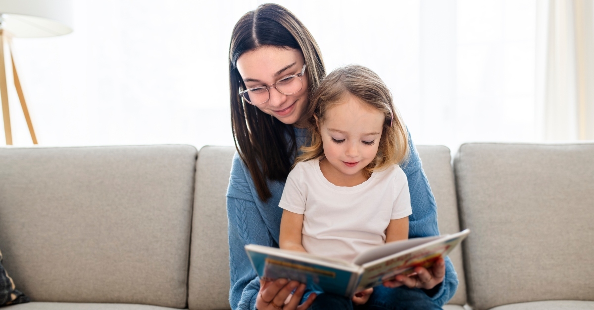 happy kid sitting on sofa with babysitter 