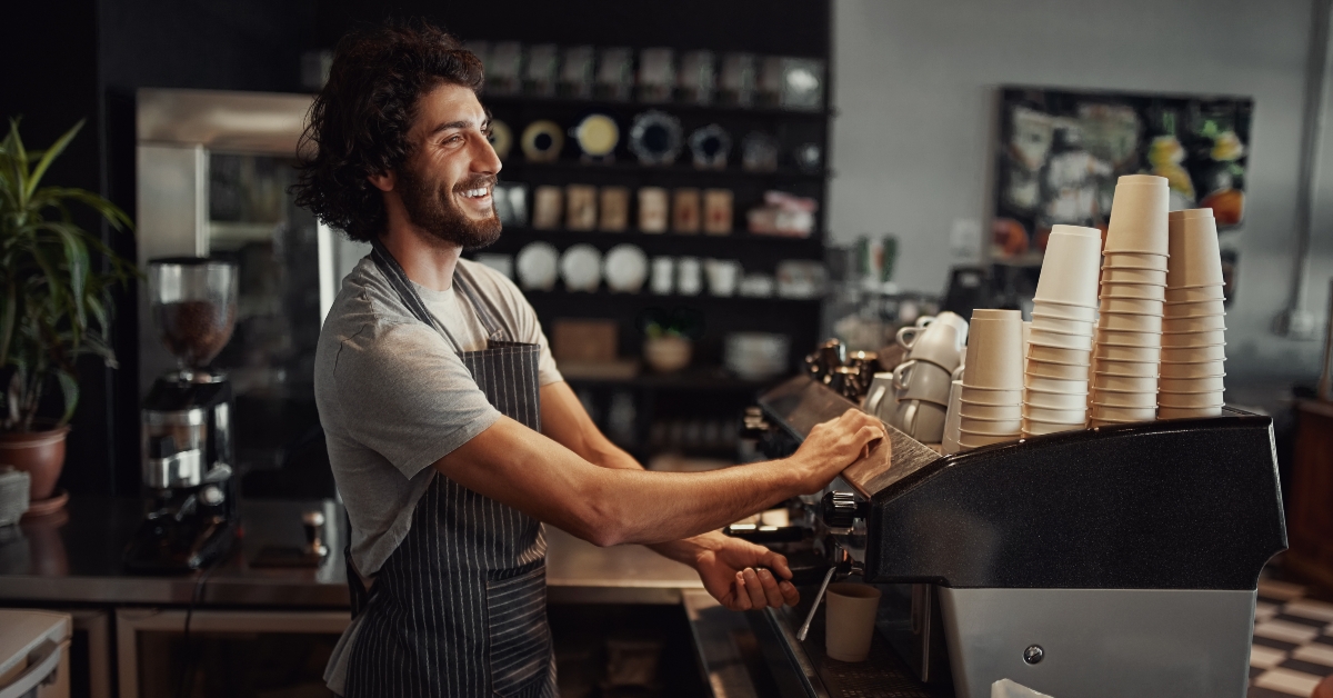 cheerful barista wearing black apron while preparing coffee