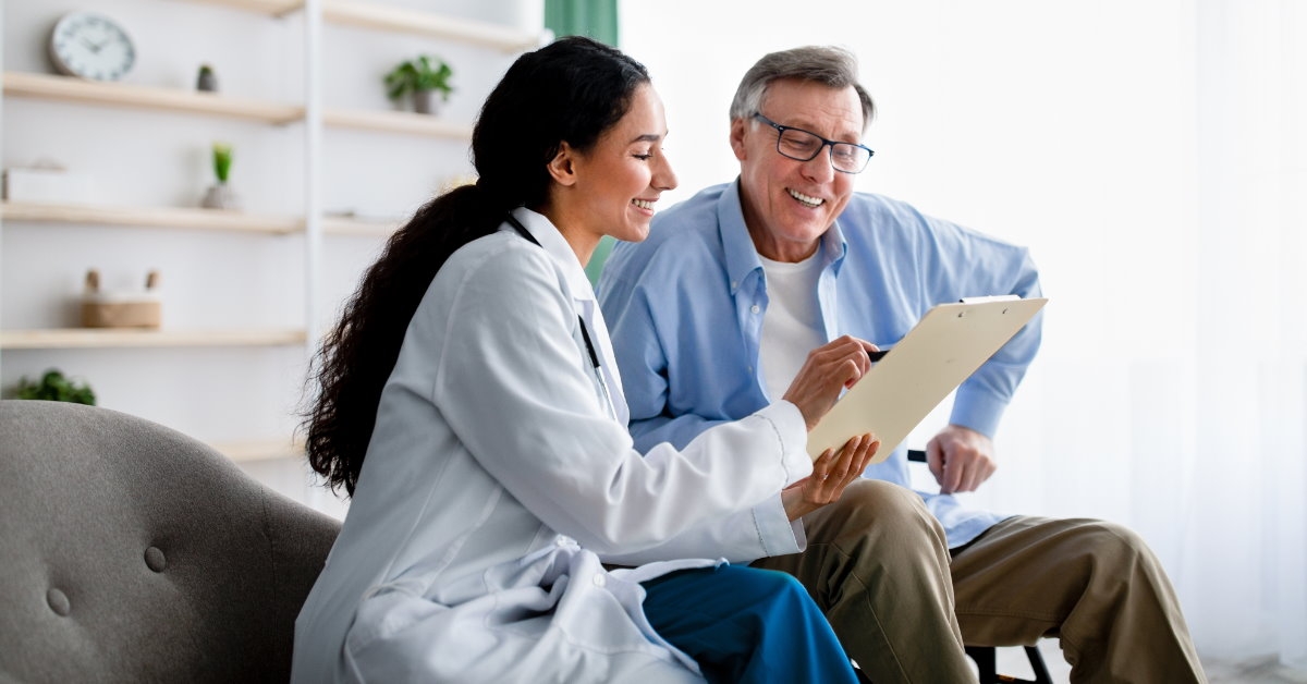 young female doctor holding clipboard and pen explaining health insurance policies to senior disabled man in wheelchair