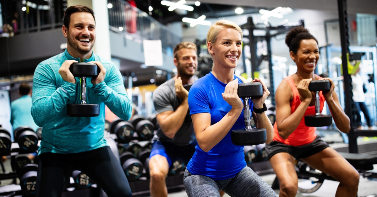 happy fit people doing exercises in gym