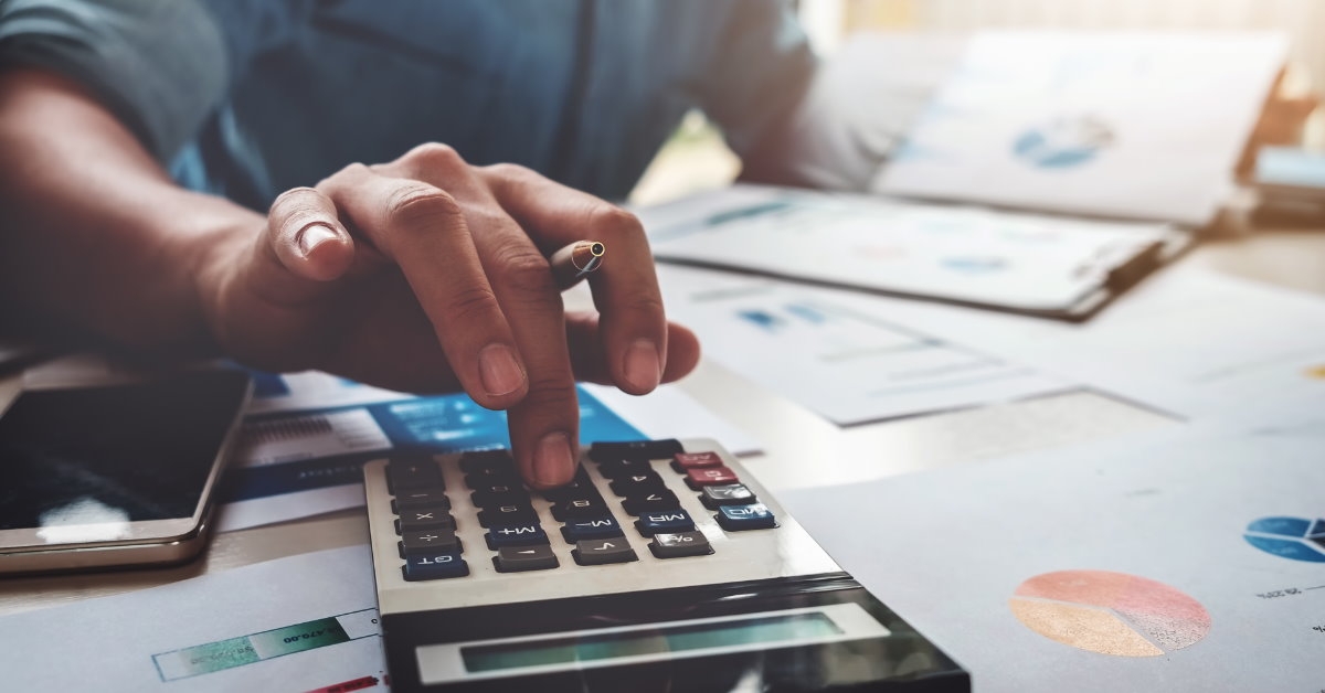 man sitting at table with files and documents using calculator 