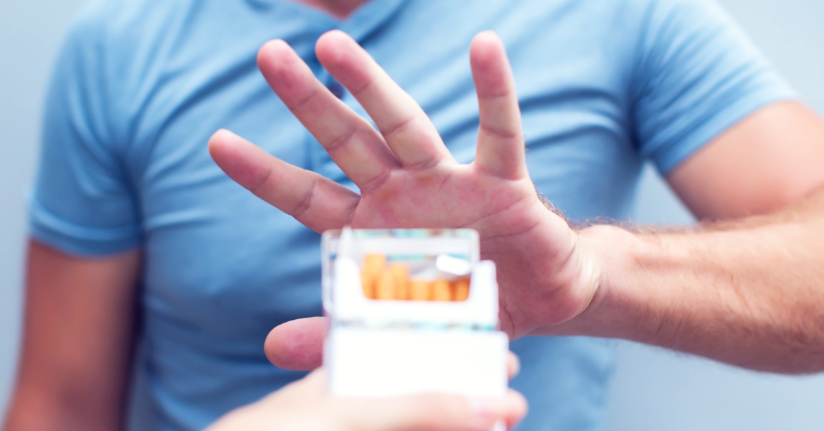 man refusing a cigarette from a pack of smokes