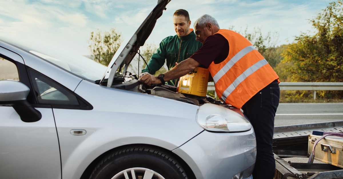 road assistant workers in towing service trying to start car engine