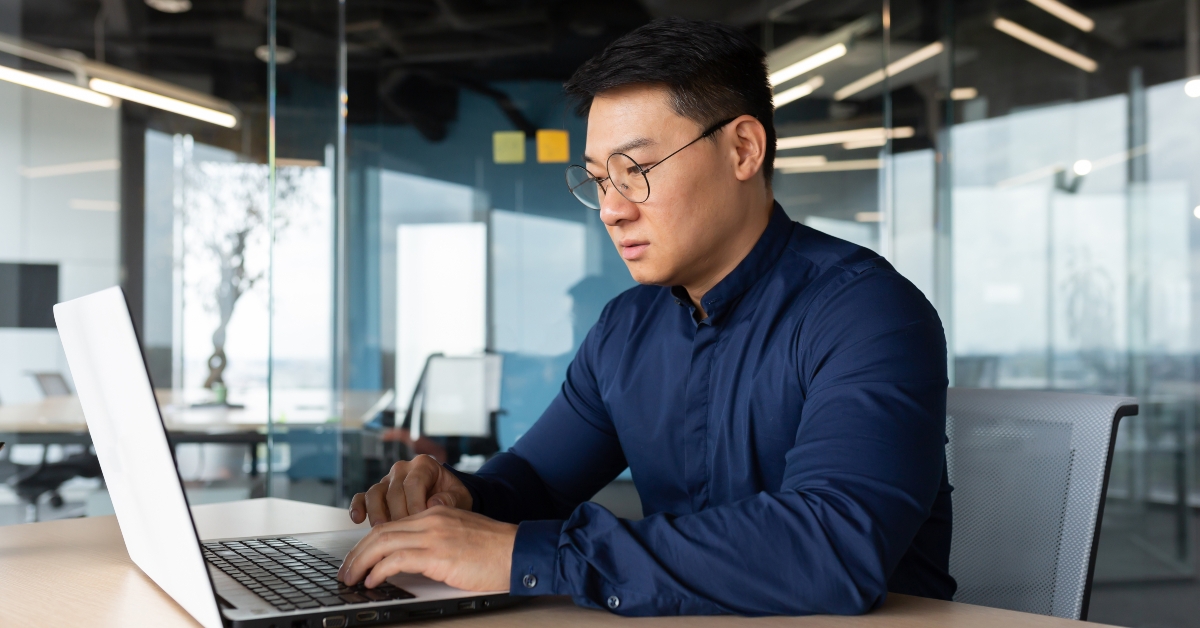 asian boss in shirt thinking and typing on laptop
