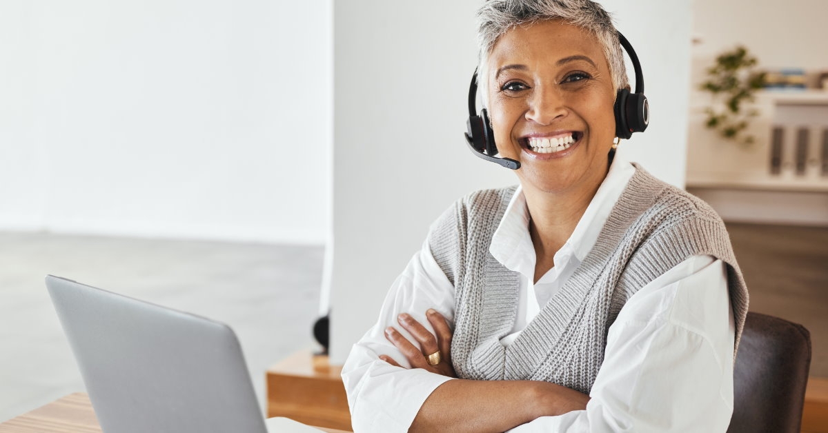 businesswoman sitting at table wearing headset smiling 