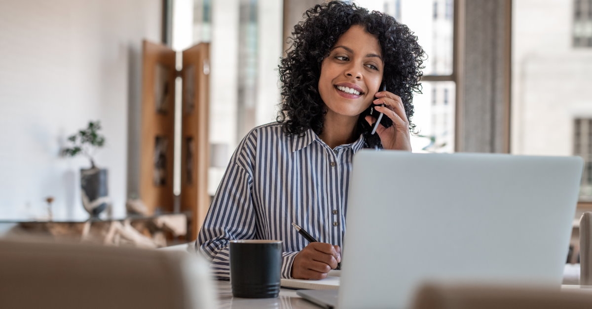 female entrepreneur working from home using laptop while talking on phone