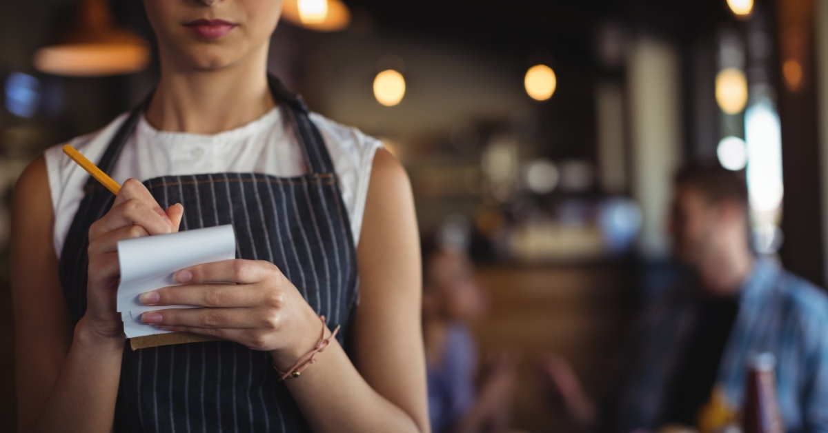 female waitress standing in restaurant wearing apron taking order 