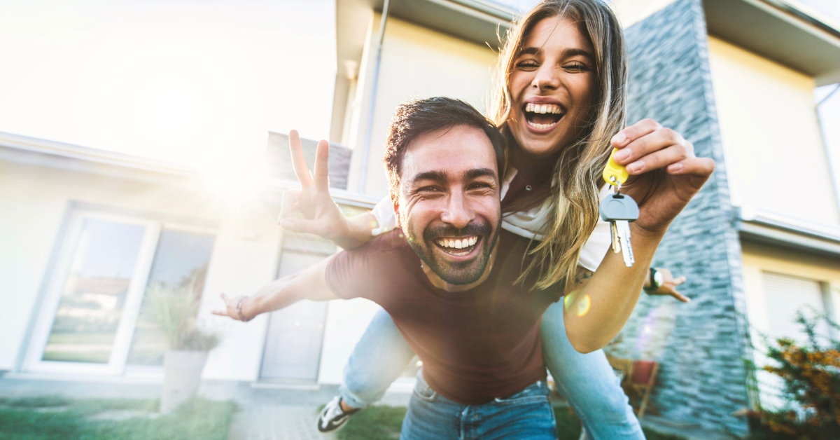 excited young couple holding keys outside new home