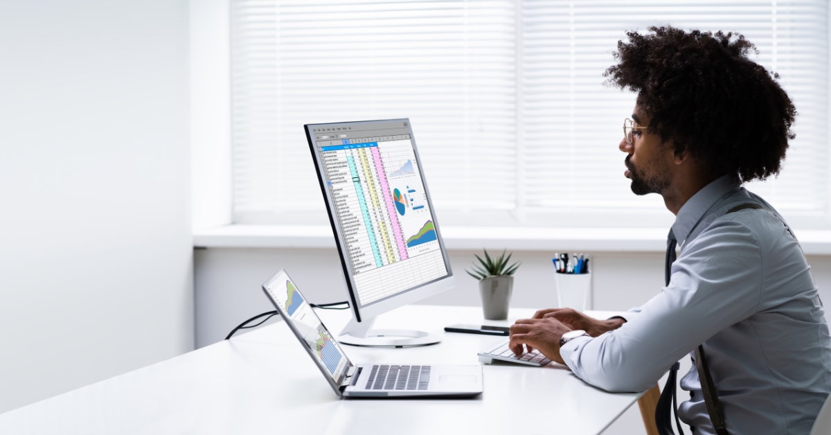 african american male analyst working on graphs and data on desktop computer