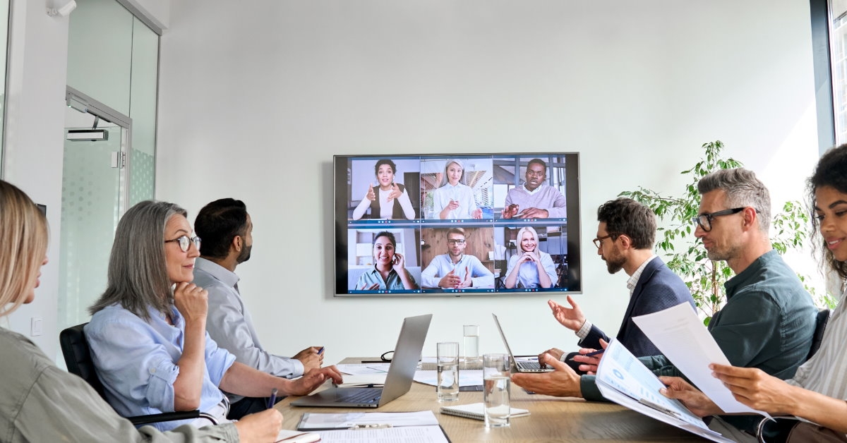 employees sitting in boardroom having video meeting 