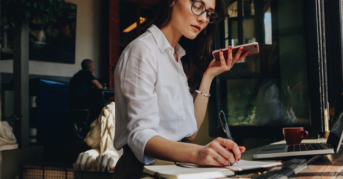 businesswoman talking on phone and making notes at cafe