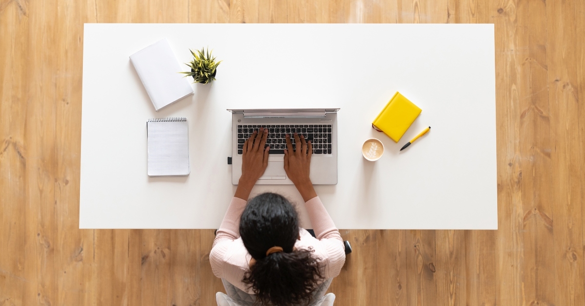 female freelancer with curly hair sitting at the white table desk 