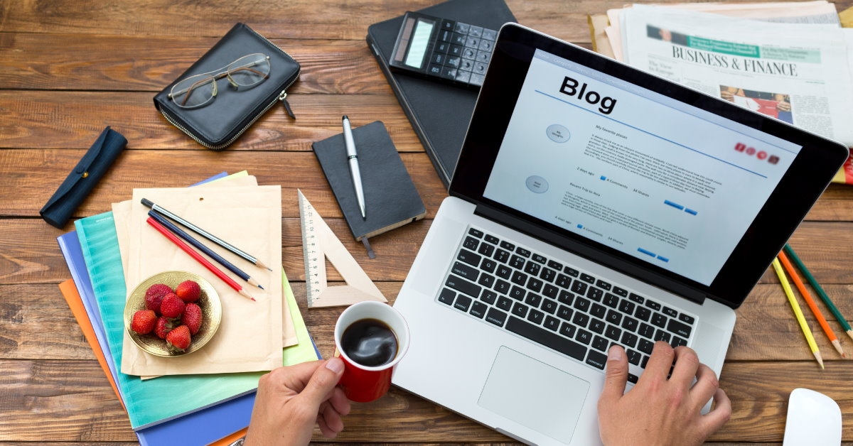man with papers and stationary using laptop to write blog