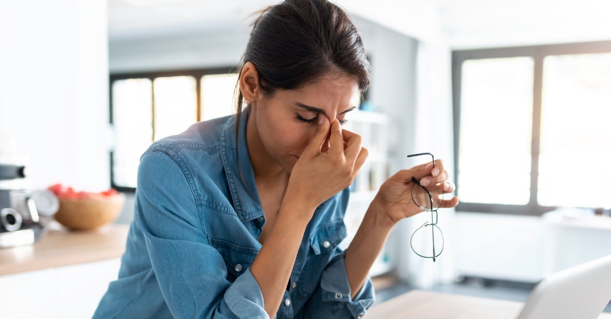 woman squinting eyes while stressing at laptop screen