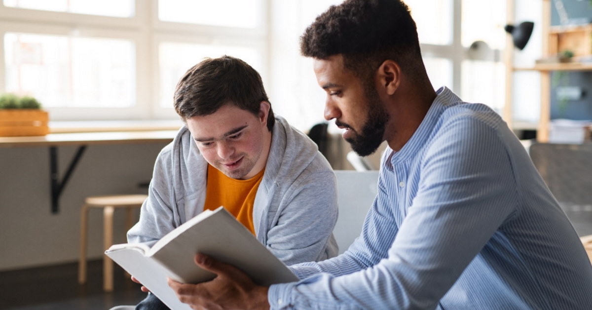 male tutor teaching young boy with down syndrome