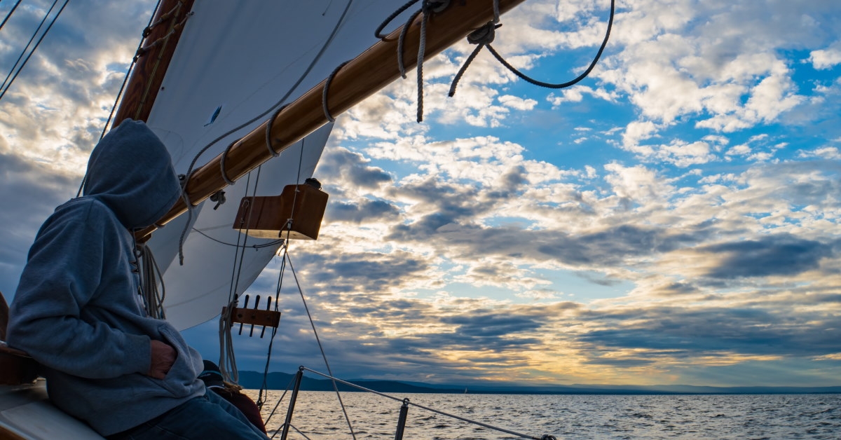 man standing in sailing schooler enjoying sunset on Lake champlain in vermont