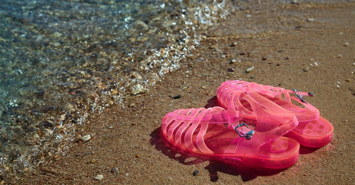 pink jelly sandals on shore at beach