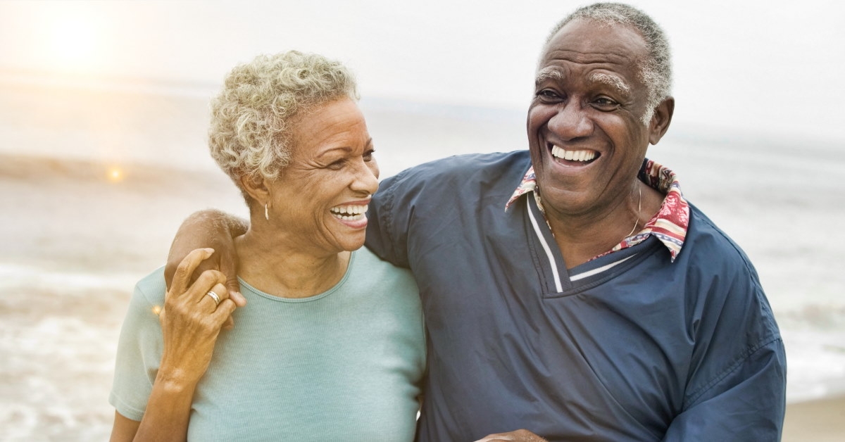 happy senior african american couple walking on beach 