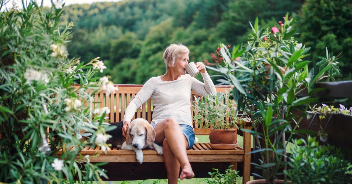 senior woman sitting on bench at terrace enjoying coffee
