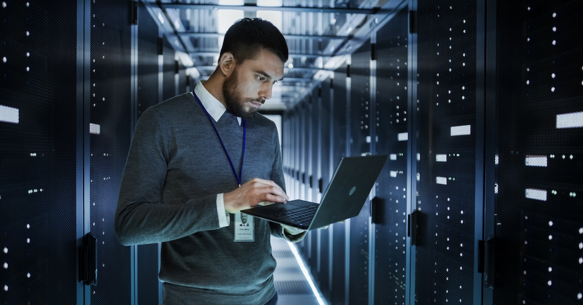 A man holding a laptop in a data center