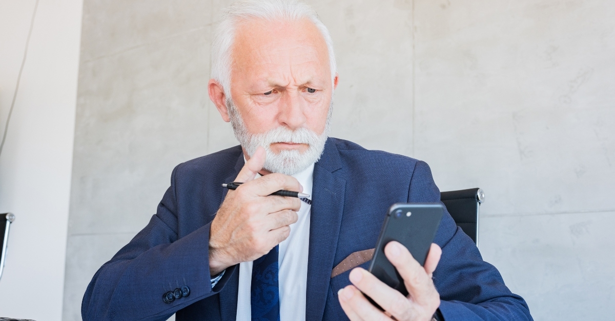 businessman using pen to write down information from phone