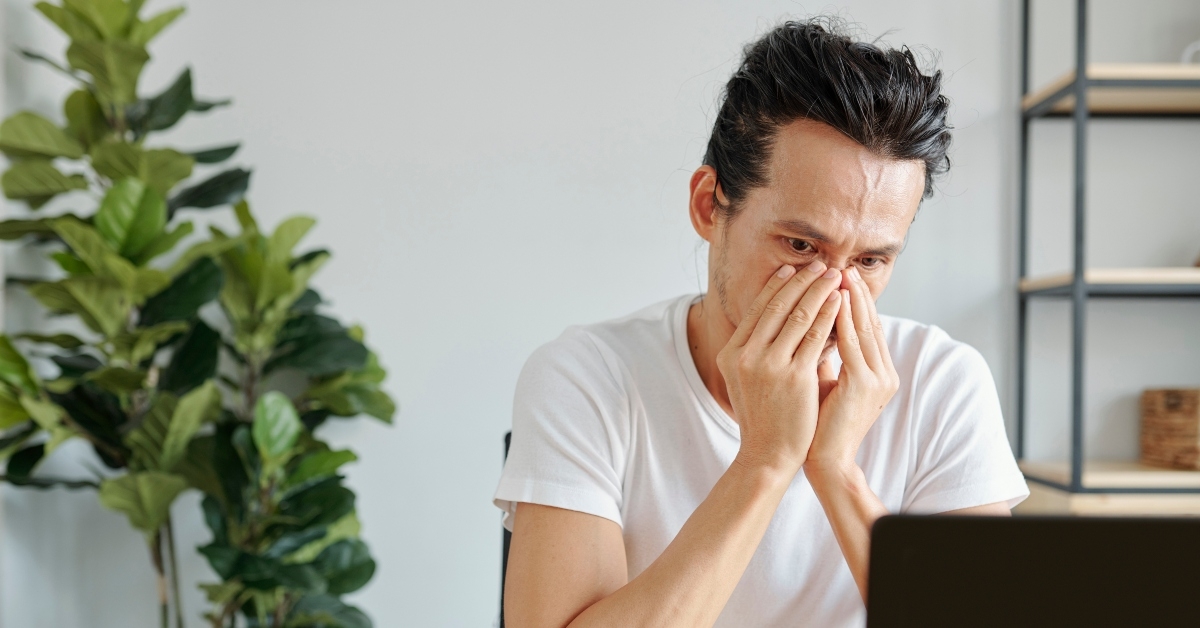 crying Asian man reading e-mail with bad news