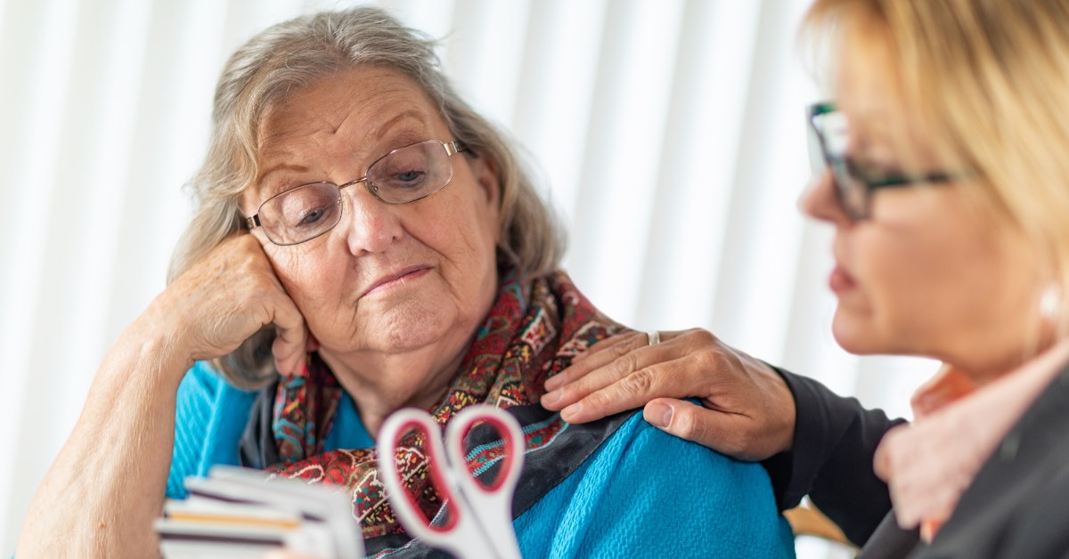 female finance advisor giving scissor to a senior lady 