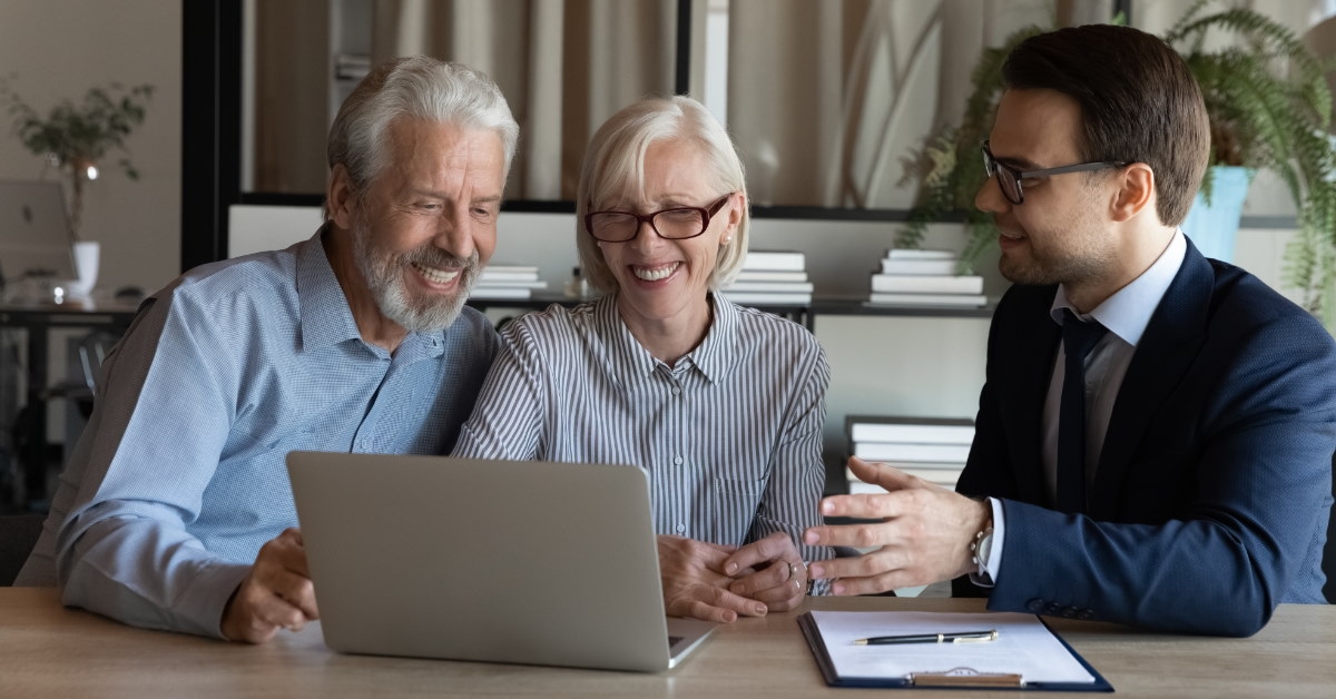 male broker showing home to senior couple on laptop