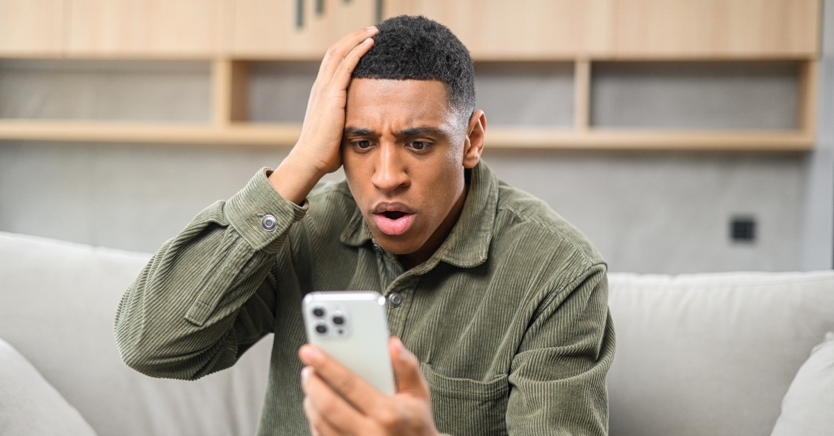 man sitting on the sofa and looking at the phone while screaming
