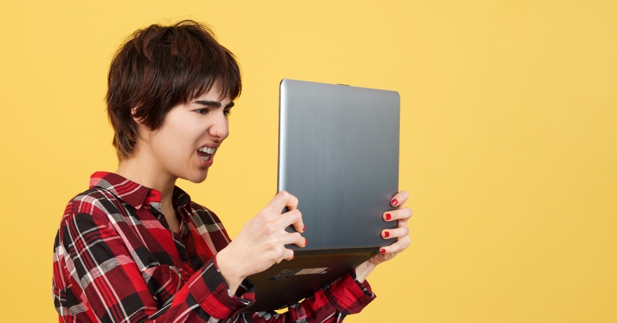 worried androgynous person standing while using a laptop