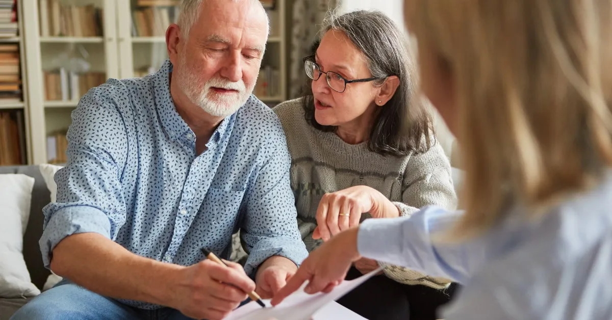 senior couple with female finance advisor signing attorney