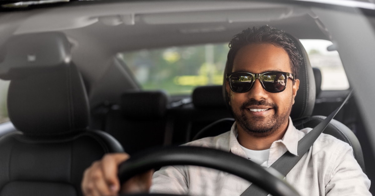 happy man sitting in the driver's seat wearing sunglasses