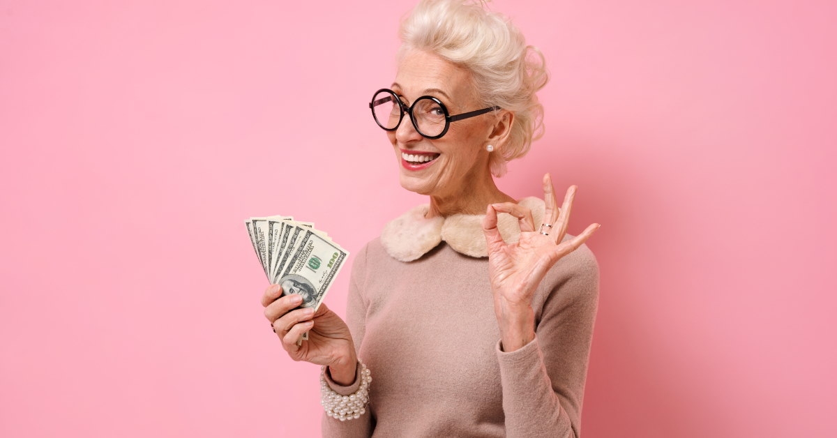 senior woman wearing glasses smiling while holding money 