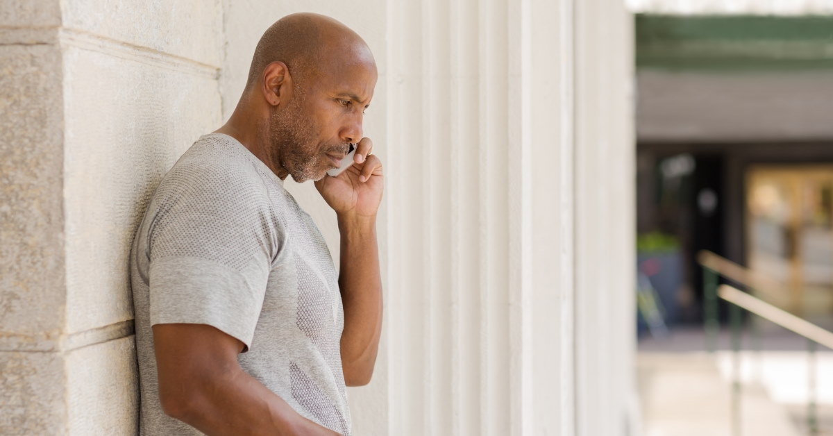 african american man standing outdoor having serious discussion on smartphone
