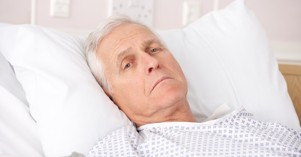 unwell elderly man lying in a hospital bed